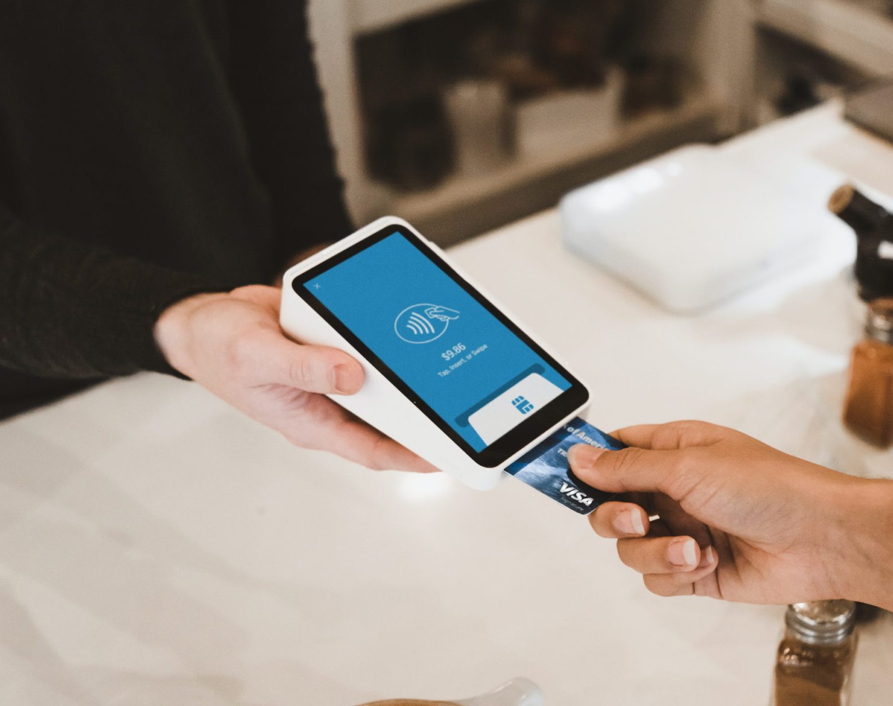 person putting magstripe card near black card terminal